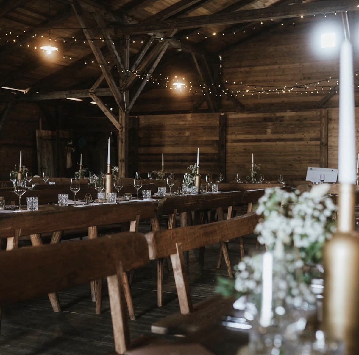 Festlich gedeckte Tafel in rustikaler Scheune mit Lichterketten